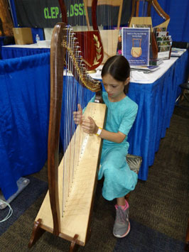 A floor stand enabling a child to sit behind a small harp
